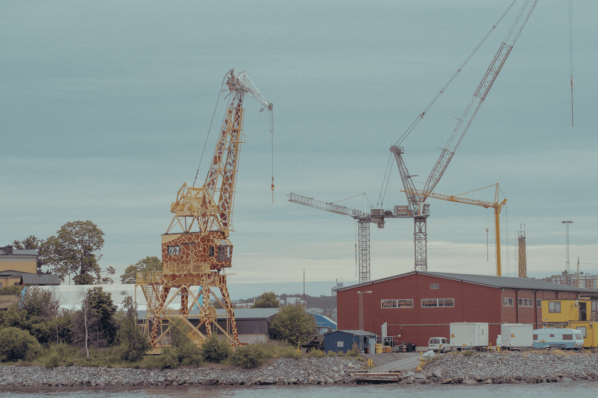 a giant yellow crane lifting a stadium seating section like a toy block