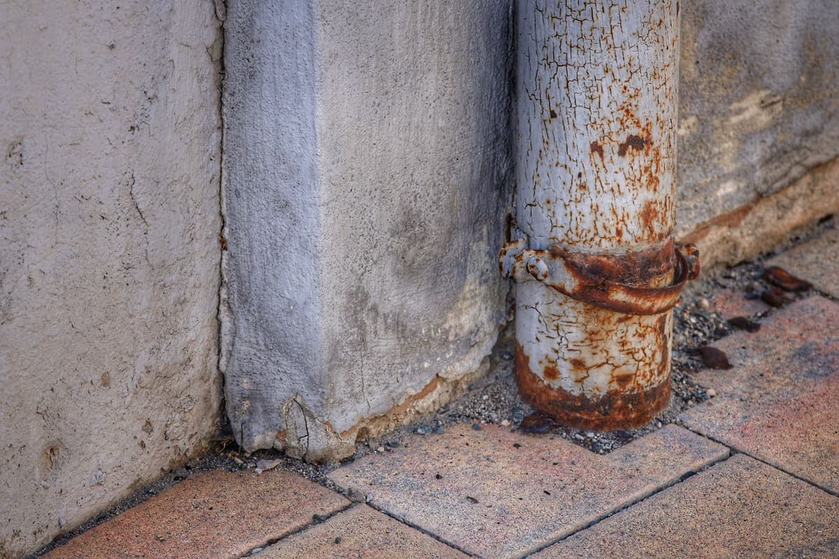 a surveyor's tripod standing on a cracked city sidewalk