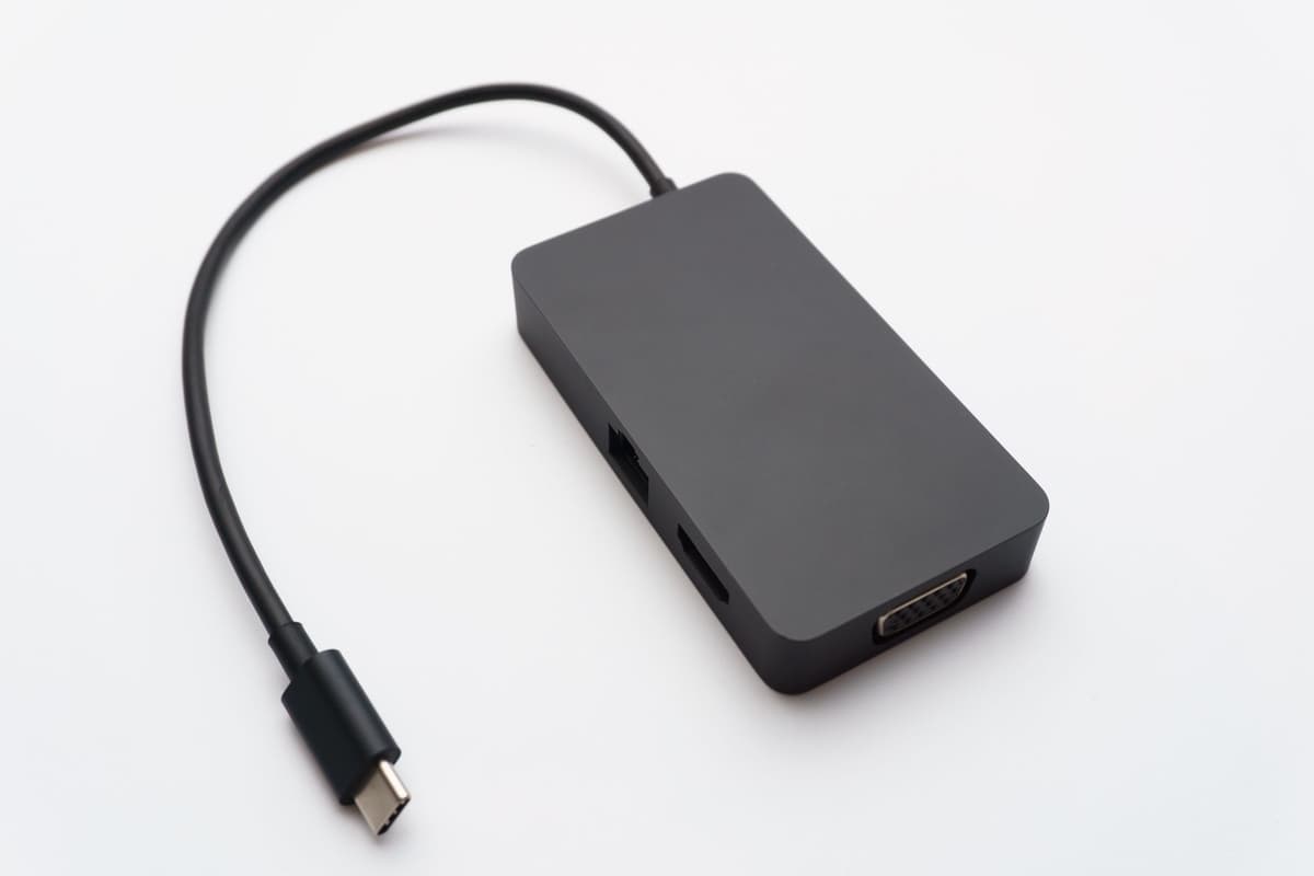 a single black USB cable lying on a plain white background, casting a sharp shadow