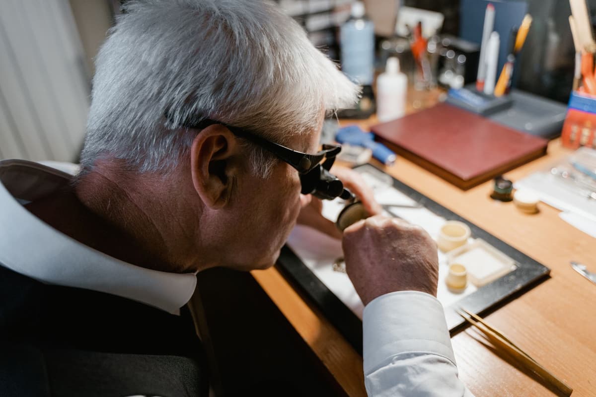 a watchmaker using loupe tweezers on gears