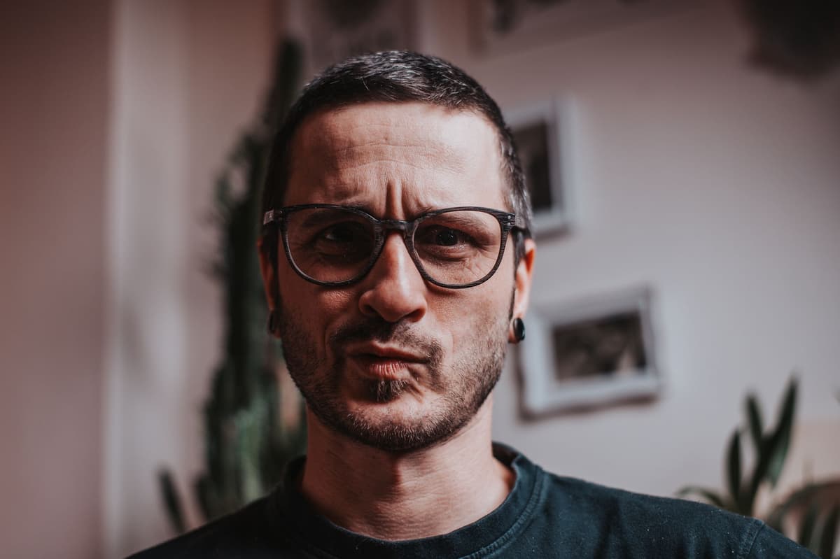a man wearing orange glasses staring intensely at a steak