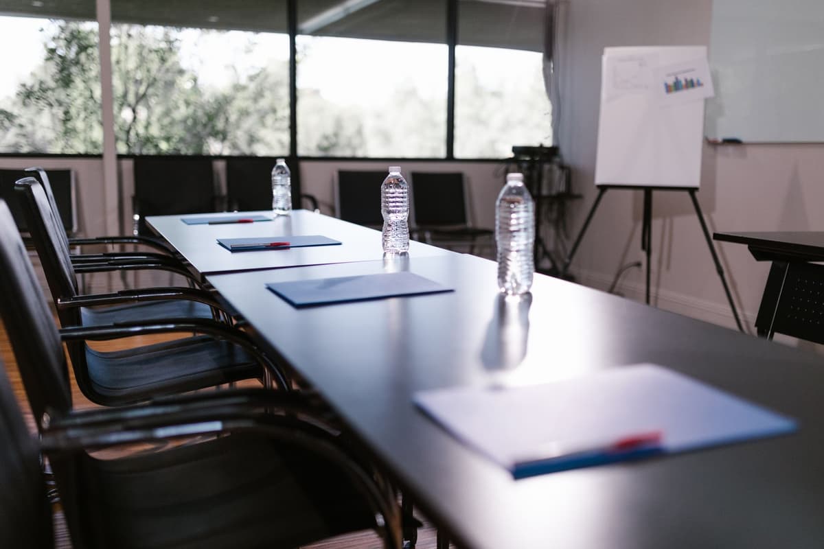 a single glass of water on a heavy wooden conference table