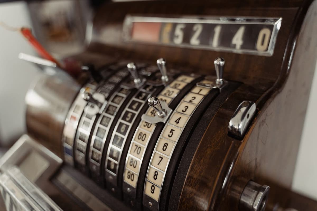 a dusty vintage cash register with a modern tablet glued to it