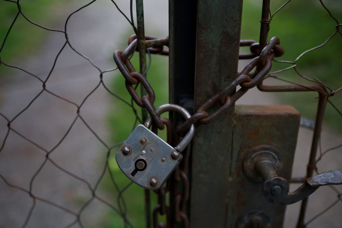 a massive rusted iron gate closing over a glowing fiber optic cable