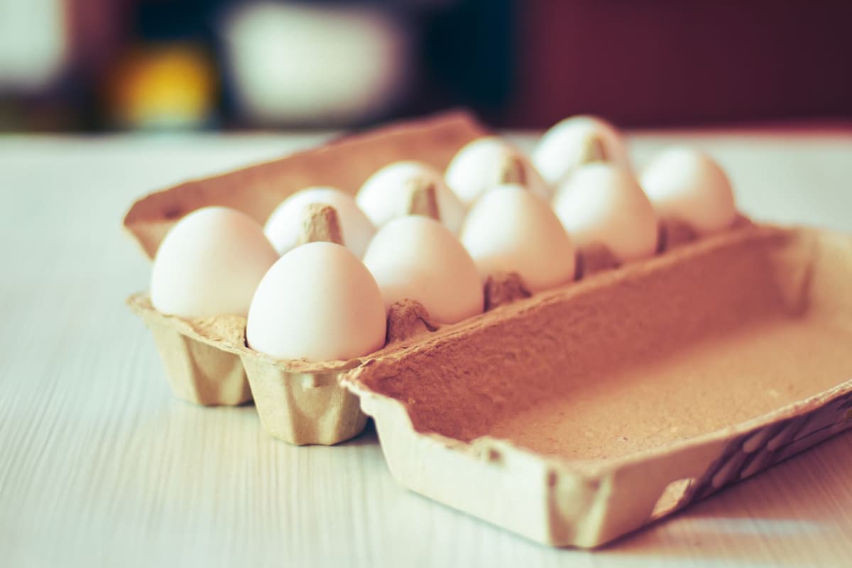 a single open carton of eggs next to a bottle of expensive gin on a kitchen counter