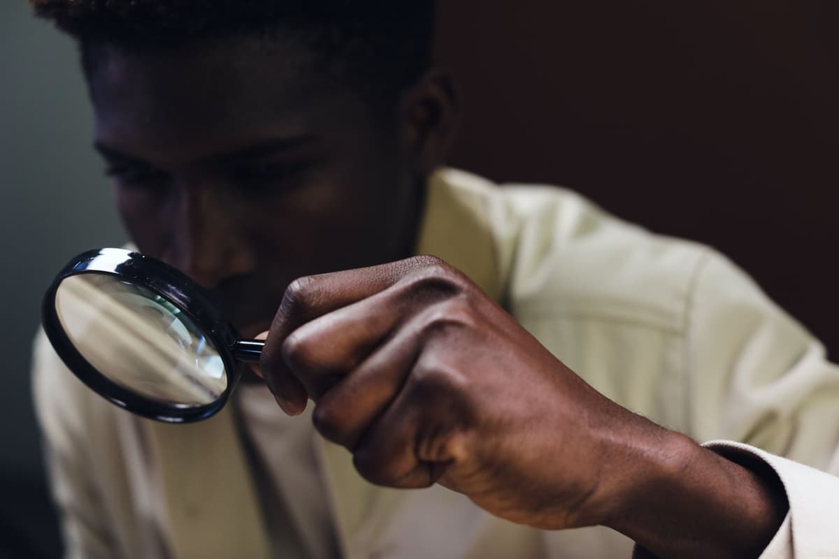 a man intensely staring at a blurry smartphone screen with a magnifying glass