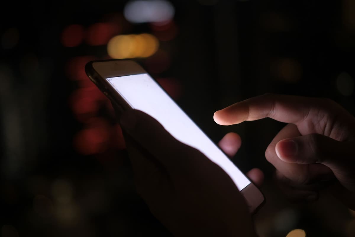 a hand holding a glowing smartphone over a stone sarcophagus