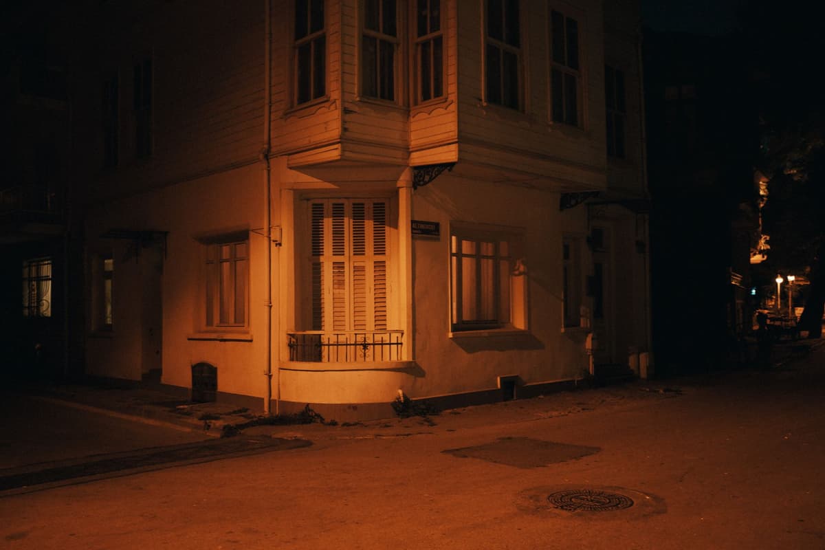 a single lit window in a dark suburban neighborhood