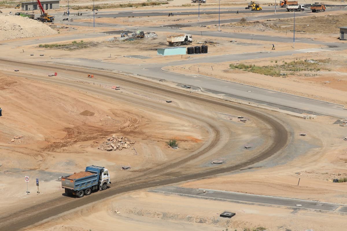 a massive dump truck pouring dirt onto a shiny stadium floor