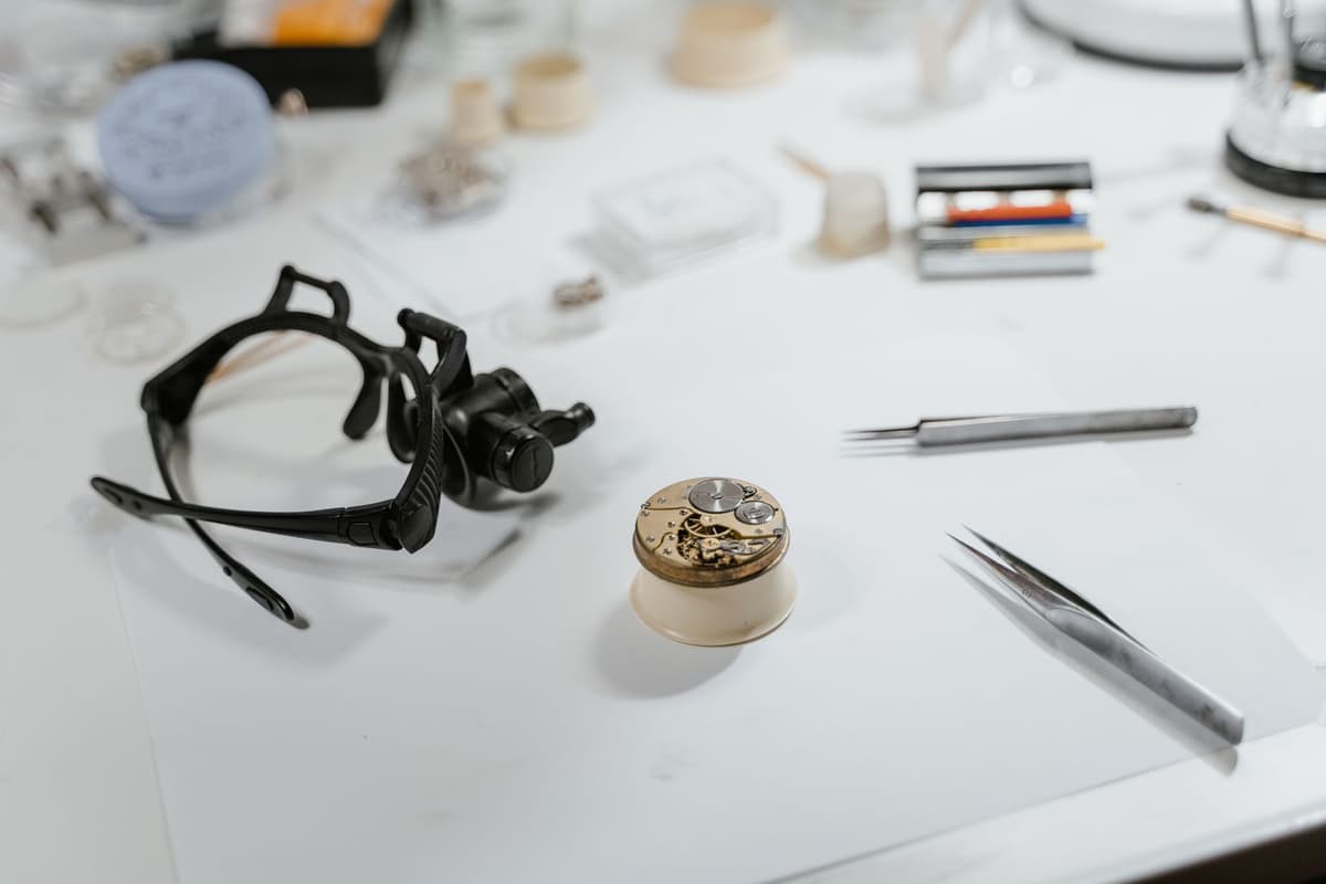 a vintage stopwatch sitting next to a complex mechanical gear assembly