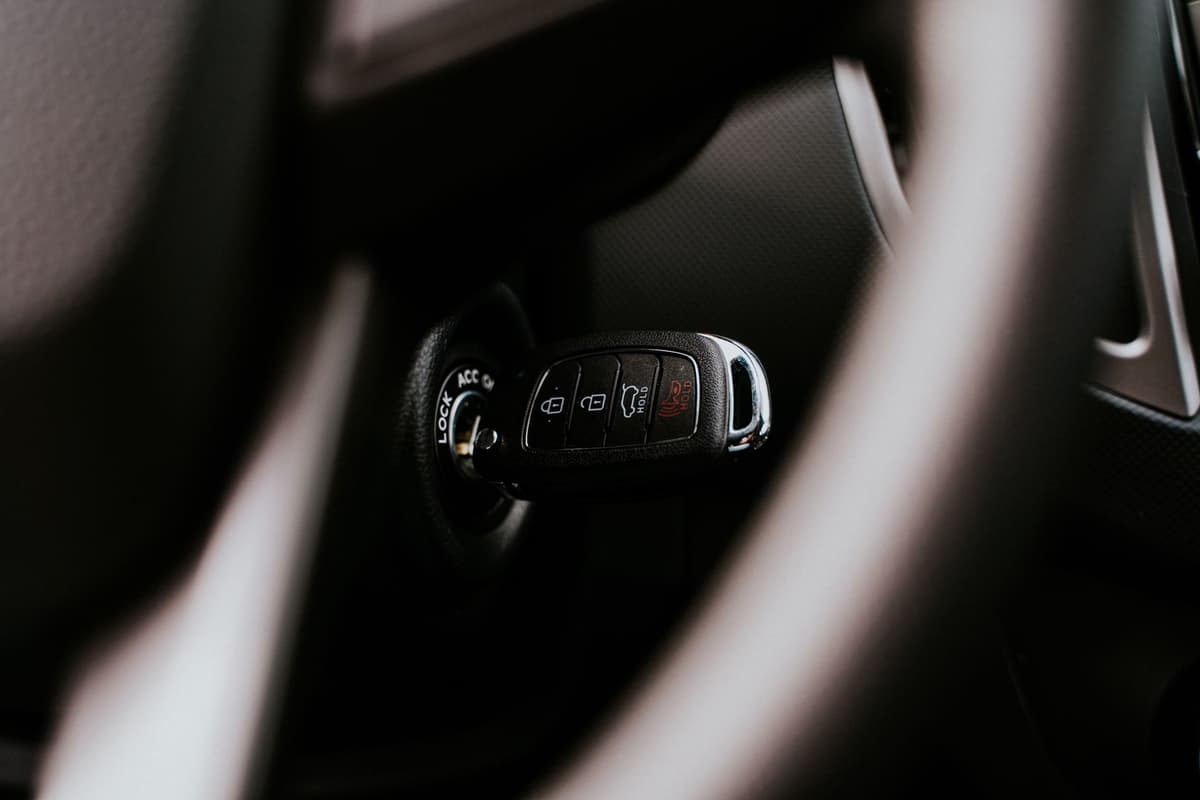 a single small white plastic tracker sitting on a dark wooden table next to a set of car keys