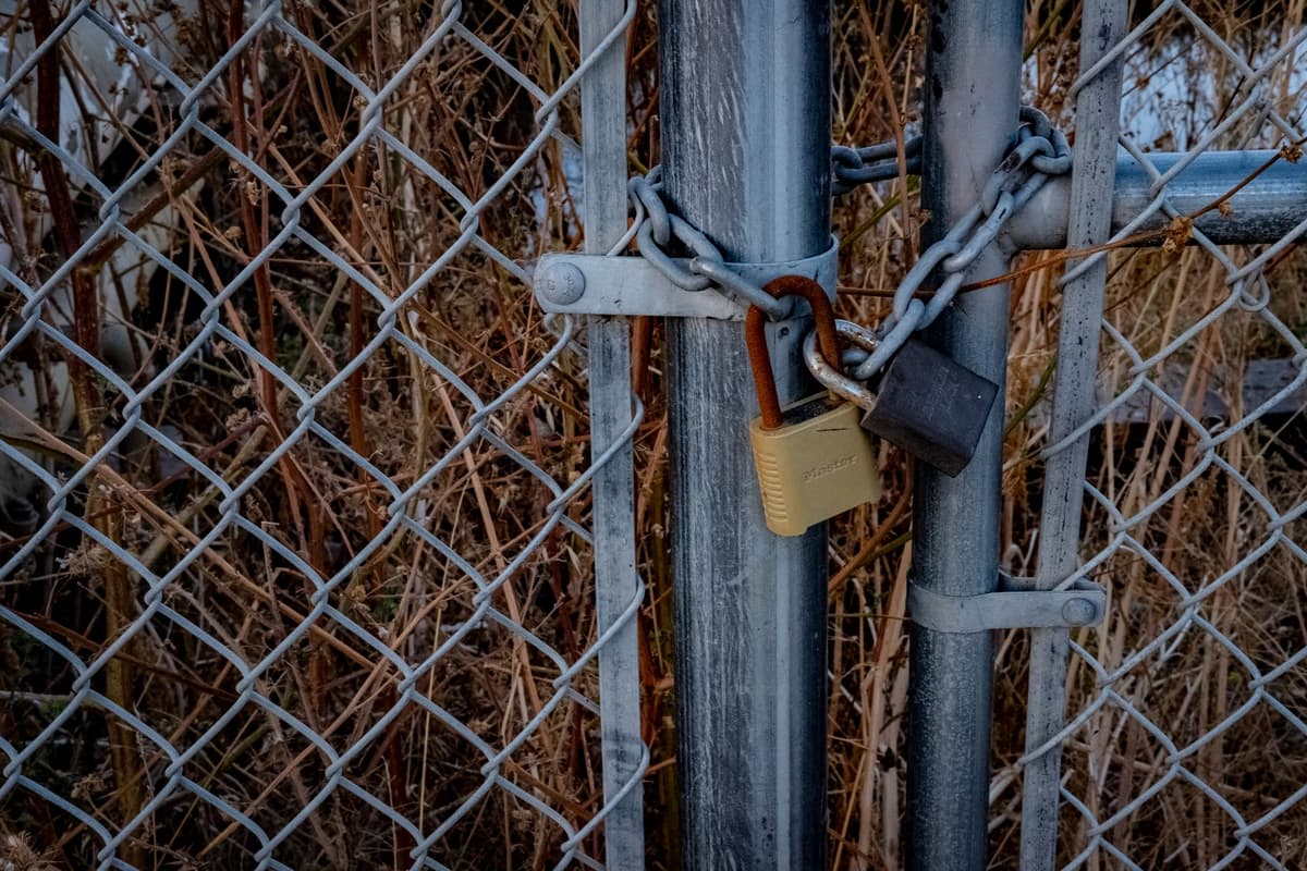 a rusty padlock on a chain link fence in front of a stadium