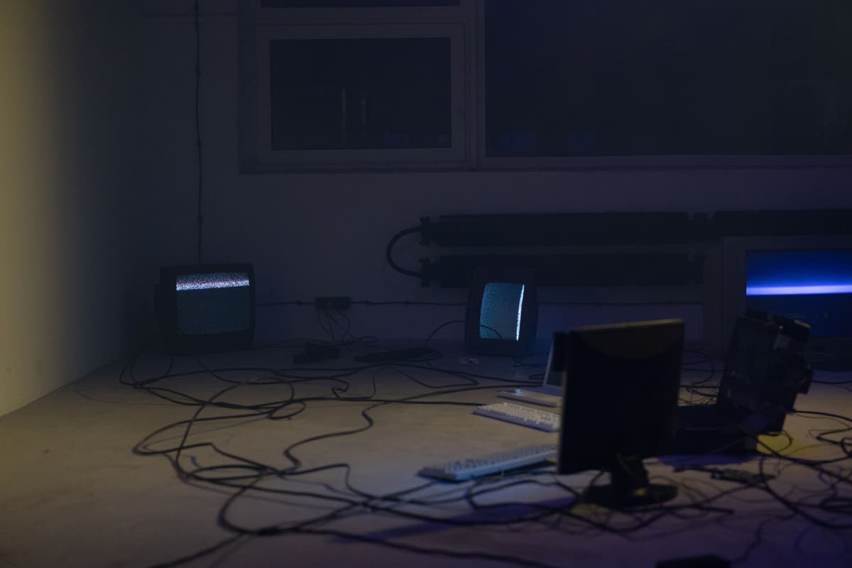 a dusty beige vintage computer monitor glowing in a dark room