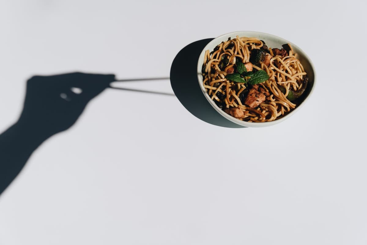 a confused robot looking at a plate of neon green spaghetti