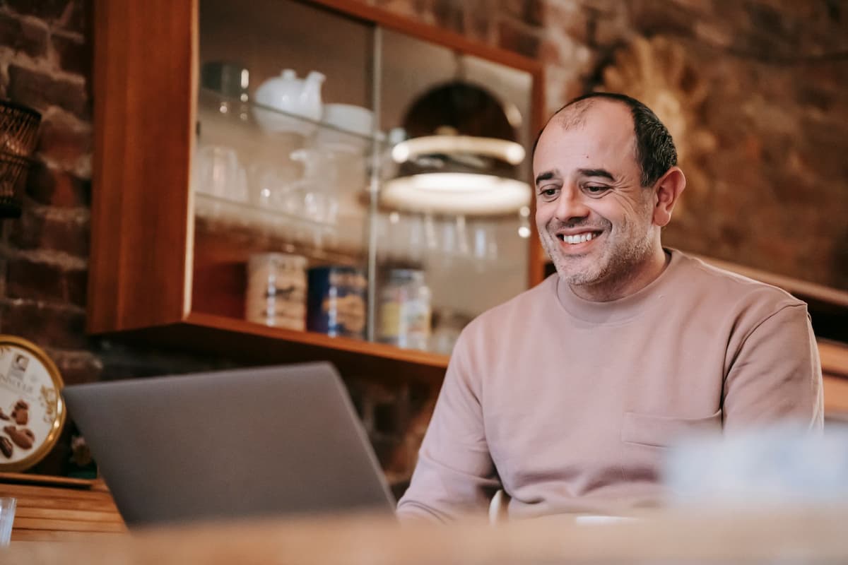 a grown man wearing a plastic helmet shouting at a laptop screen