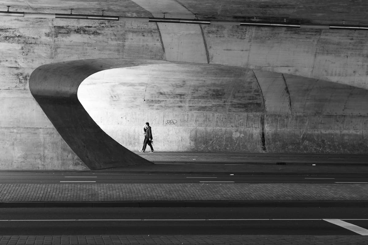 a single person waiting at a red pedestrian light on an empty street