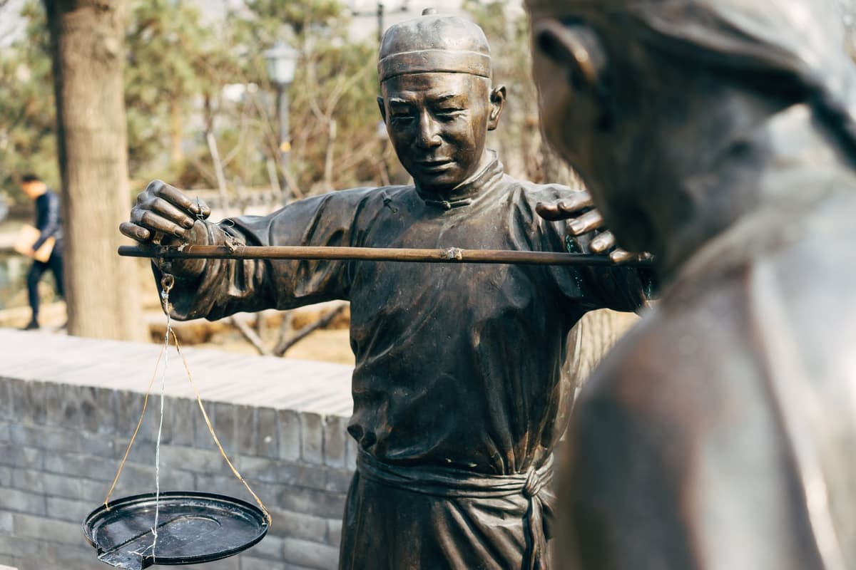 a dusty ancient bronze statue pouring liquid into a cup