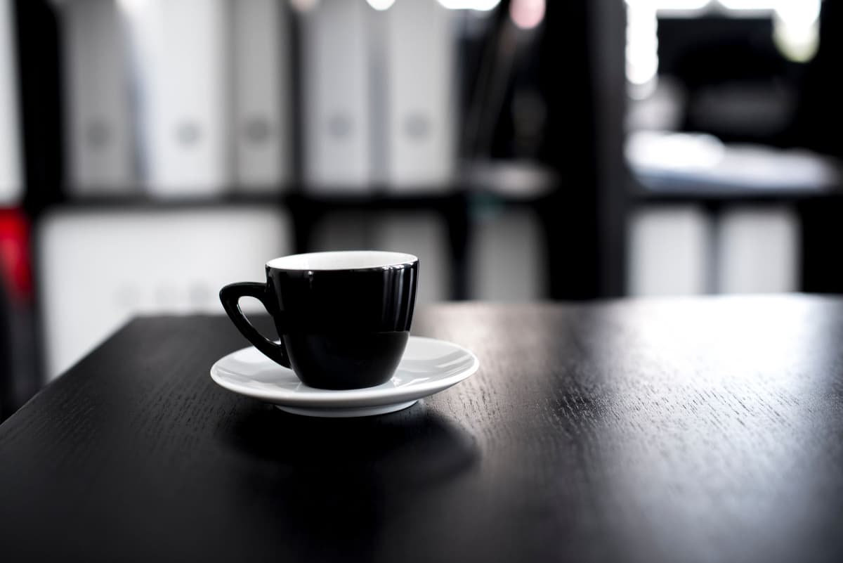 a single empty coffee cup on a cluttered desk