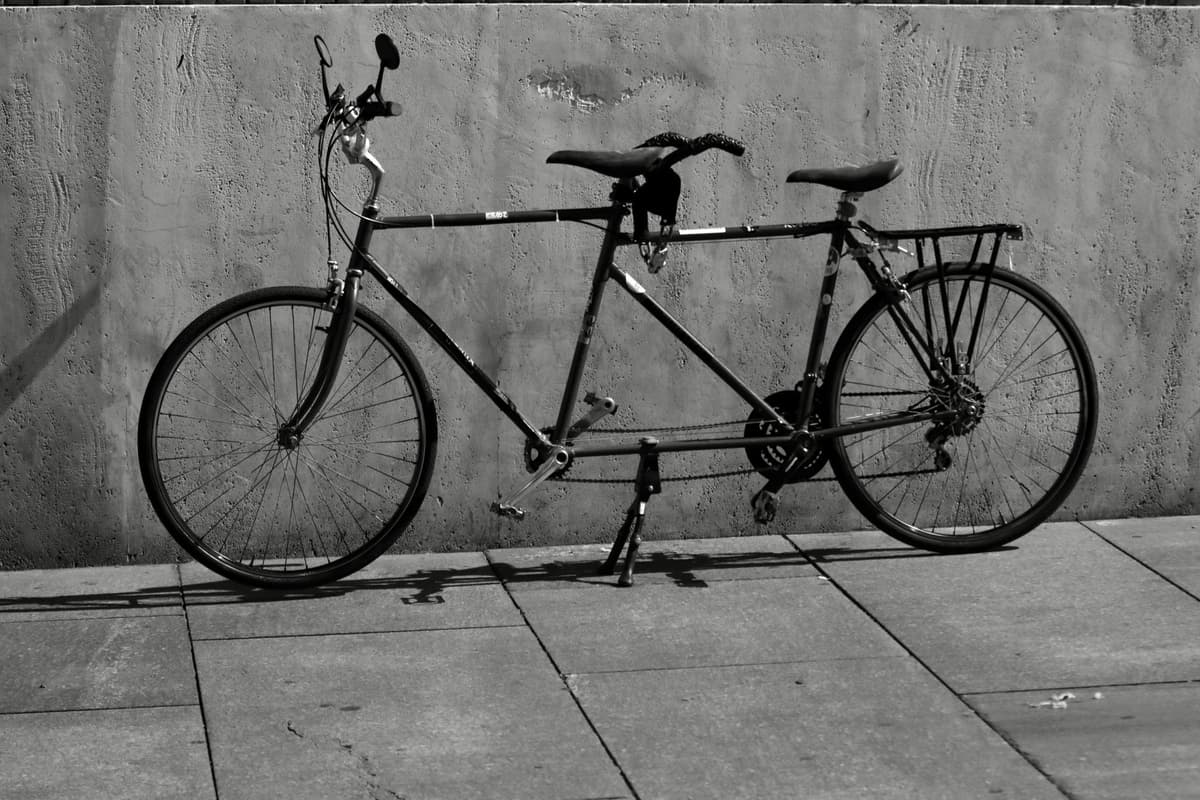 two bicycles leaning against a white picket fence
