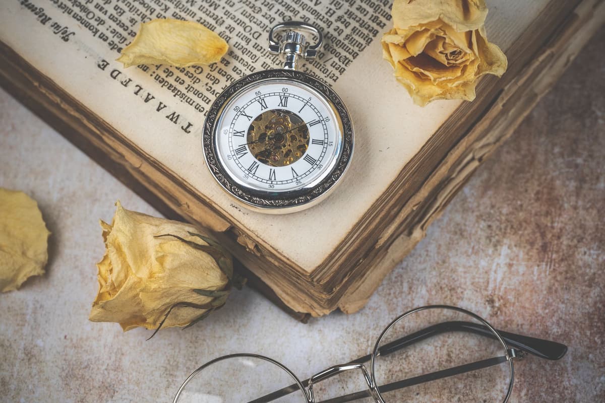an antique pocket watch open on a wooden table beside a circuit board
