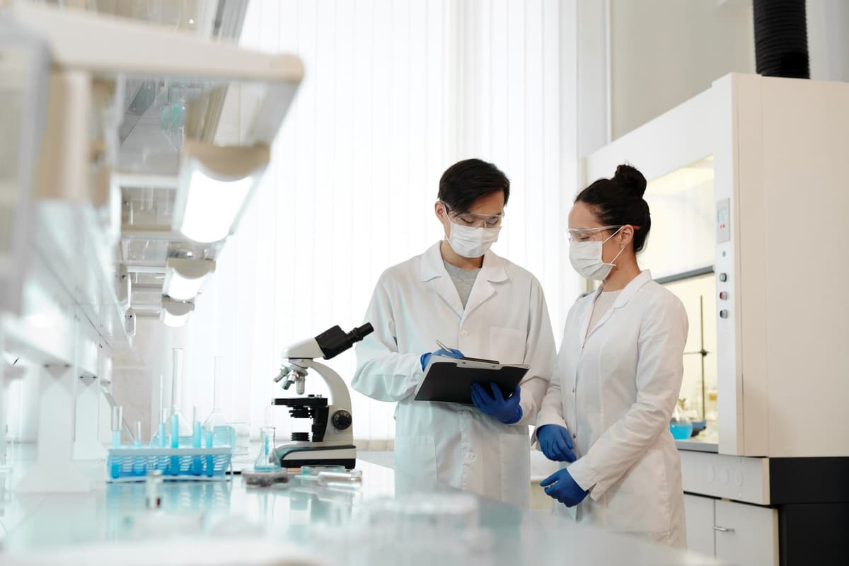 scientist in white lab coat holding a wooden clipboard
