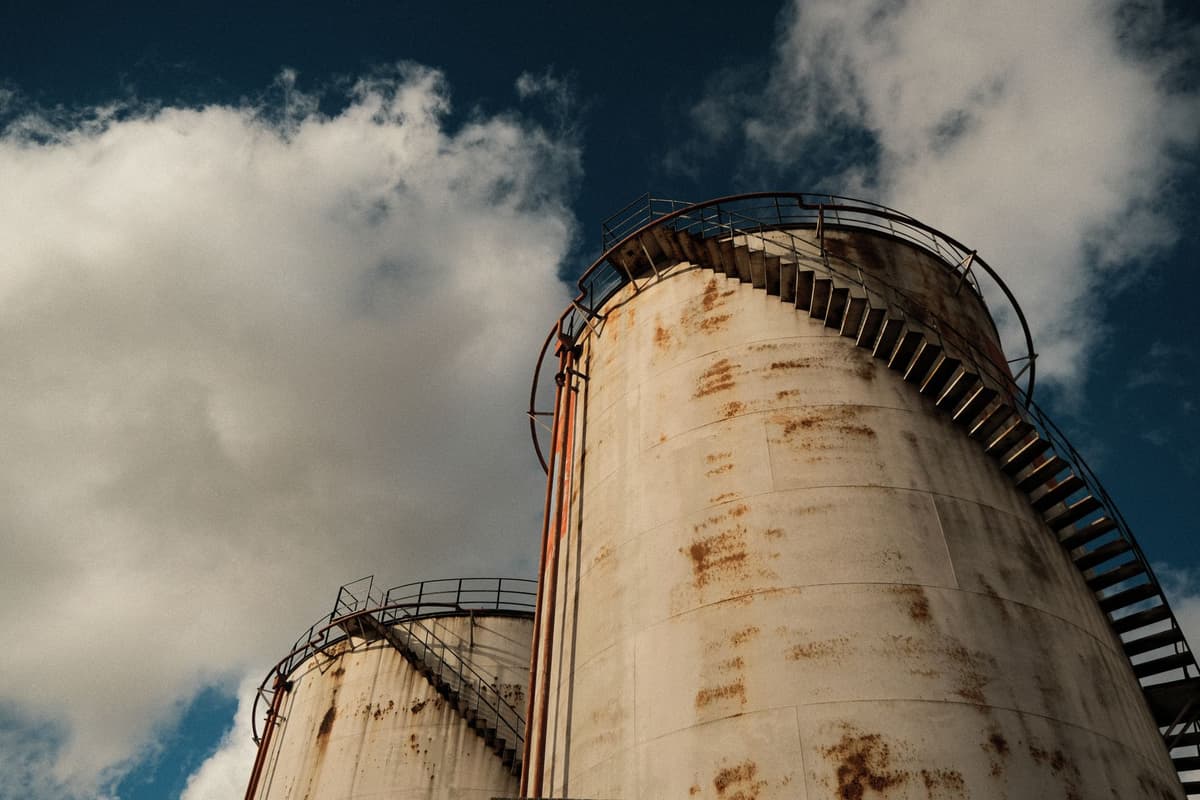 a single rusted grain silo in a barren field