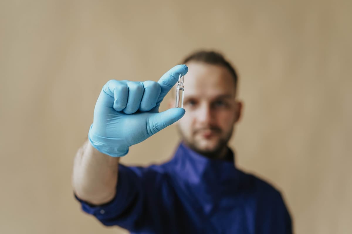 biologist in a cleanroom handling a small glass vial