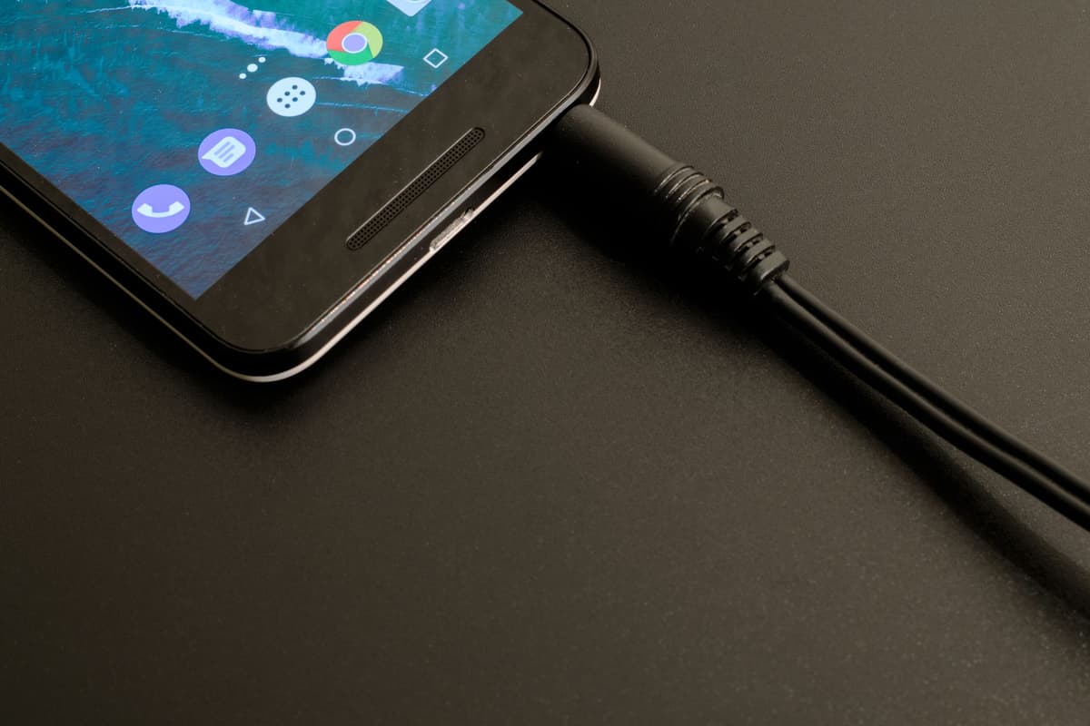 a row of identical black smartphones on charging racks