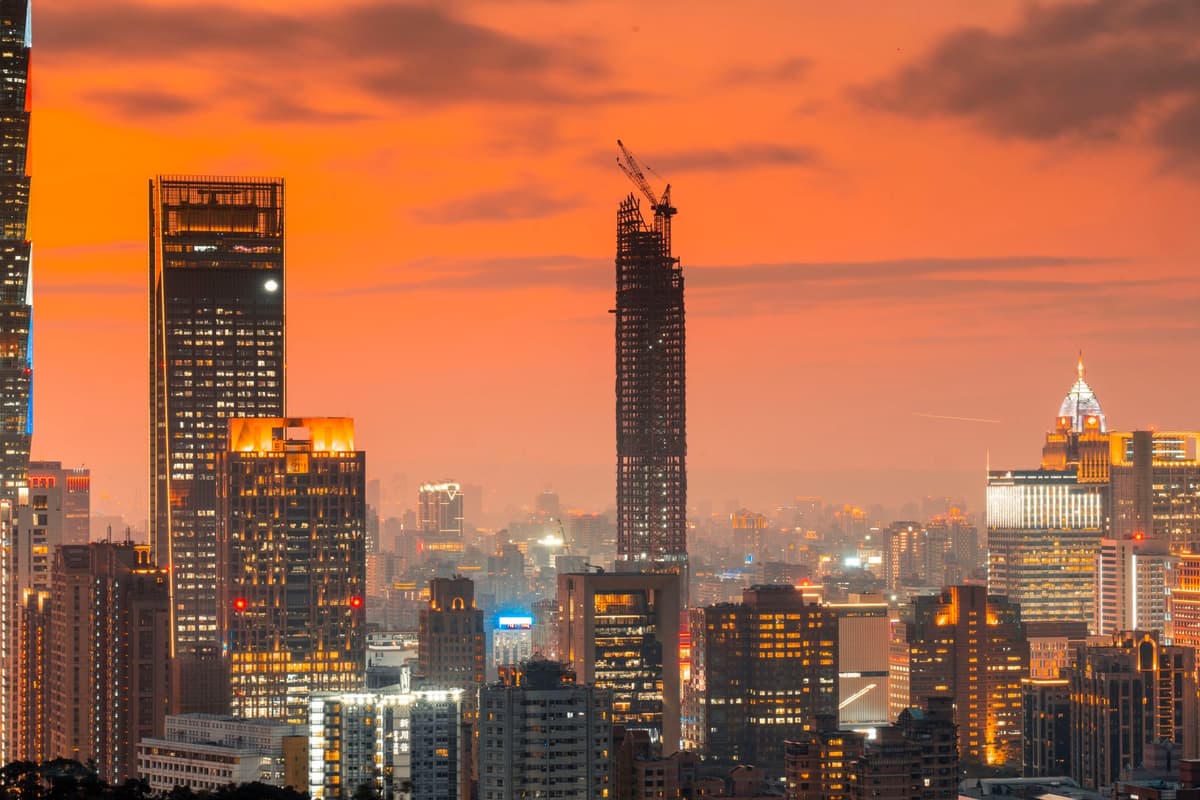 a glass skyscraper reflecting a dark orange sunset through smog