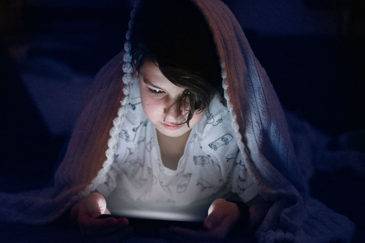a person staring intensely at a glowing smartphone in a dark kitchen