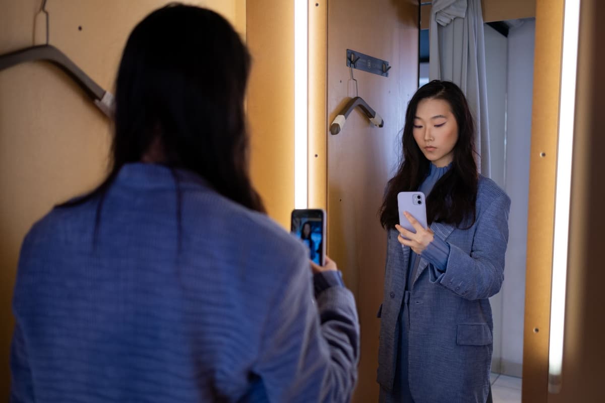 a person holding a glowing smartphone in a dark mirrored room