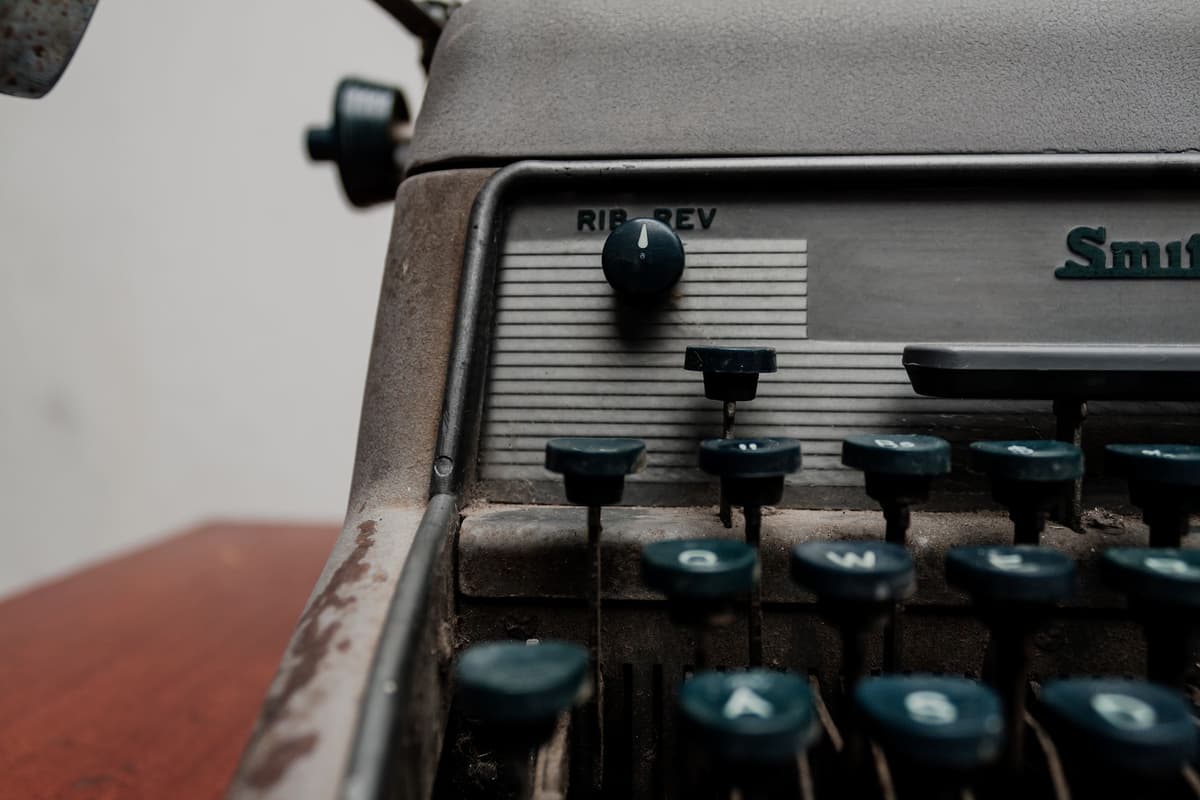 a close-up of an old typewriter sitting next to a modern high-end laptop