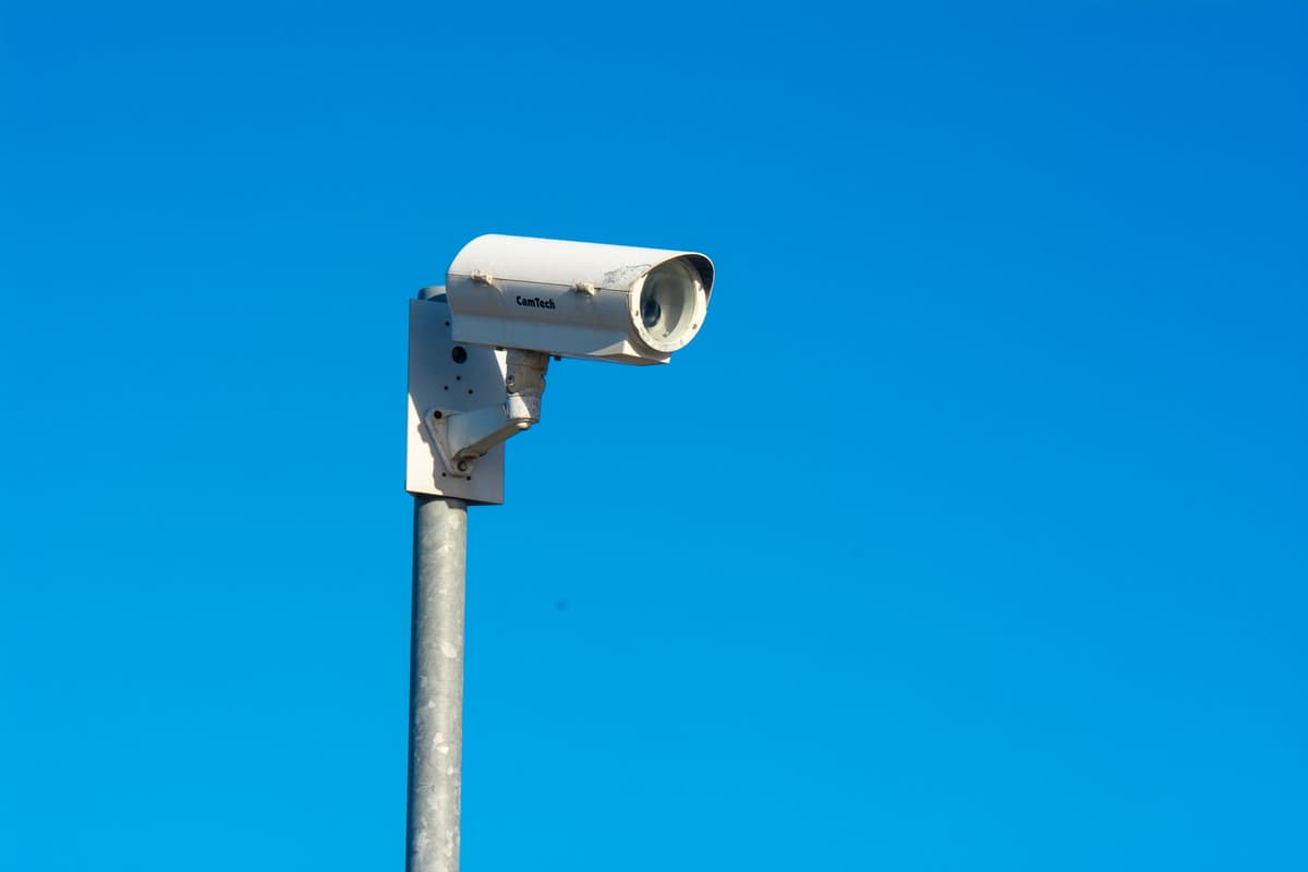 a bright red cardinal landing on a high-tech security camera