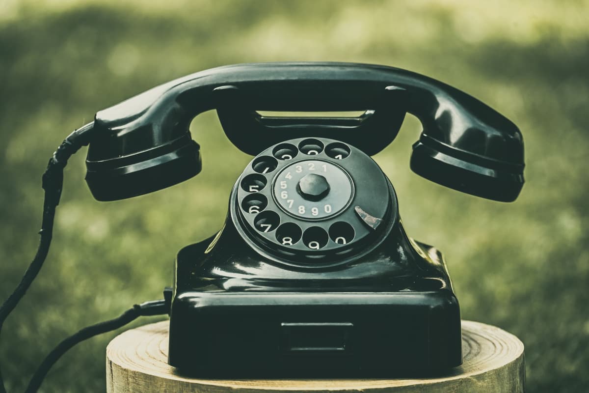 a dusty black rotary phone on a wooden crate