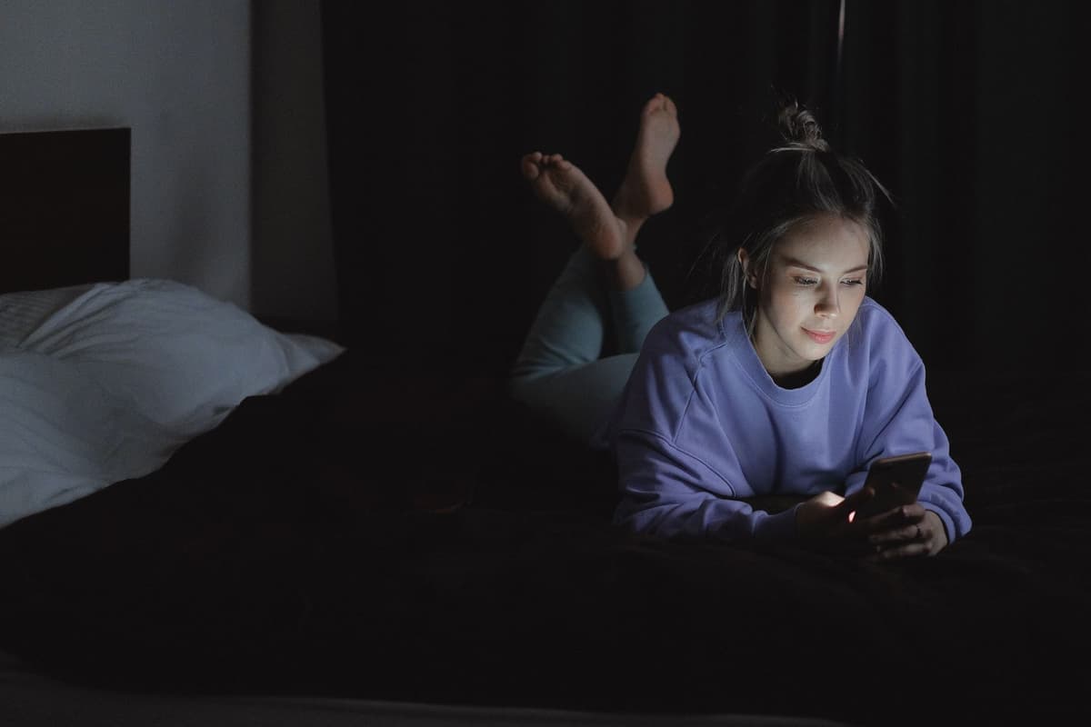a person scrolling endlessly on their phone in a dimly lit room