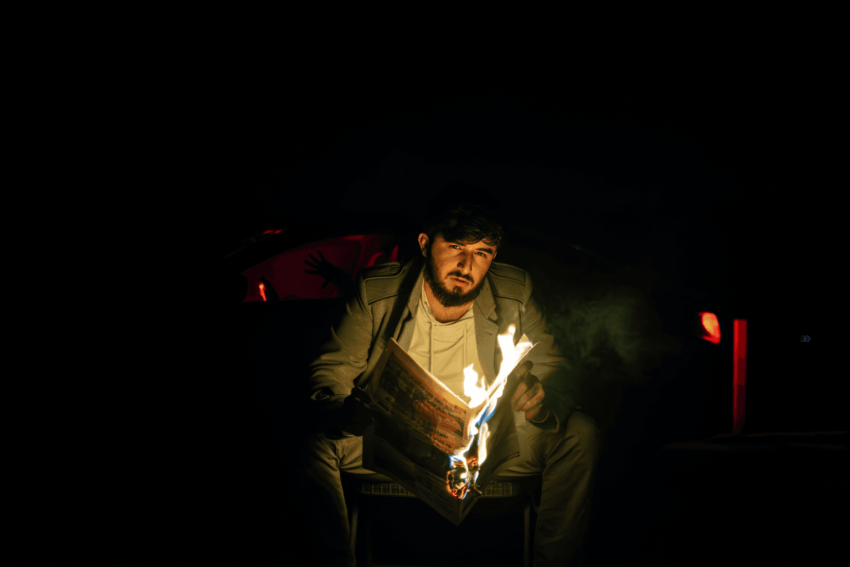 a man in a corporate suit shrugging next to a burning film reel