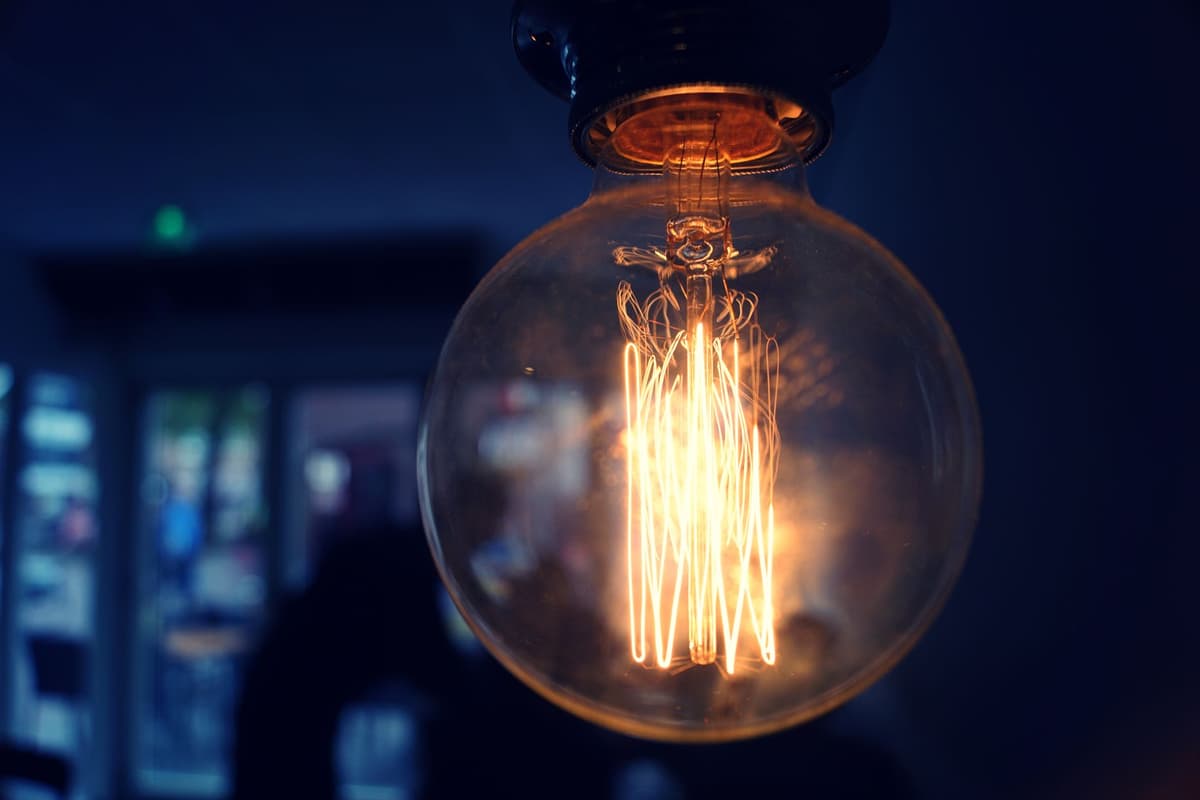 a single red light bulb hanging over a dark alleyway gateway