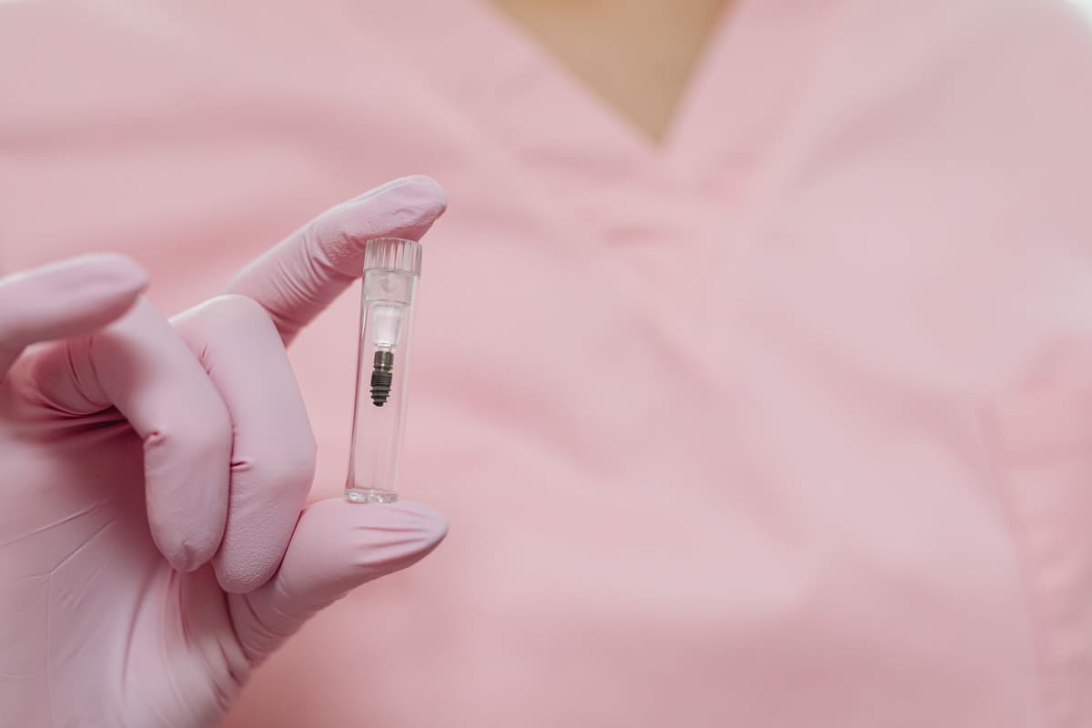 a researcher in a silver proximity suit holding a tiny test tube