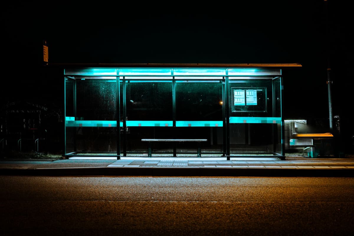 a person staring intensely at a glowing smartphone screen at a dark bus stop