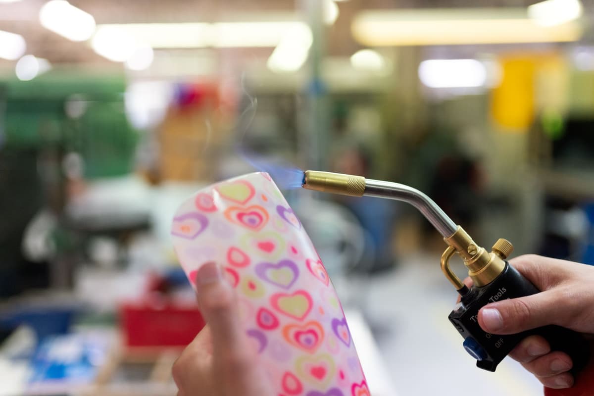 a technician using heat guns to melt adhesive on a sleek glass phone