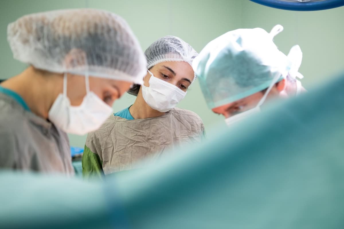 a surgeon holding a tablet over a patient's torso