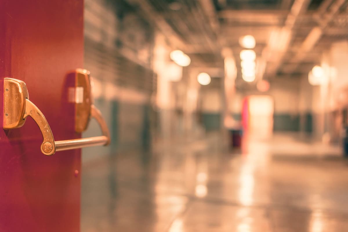 person staring at hundreds of identical doors in empty hallway