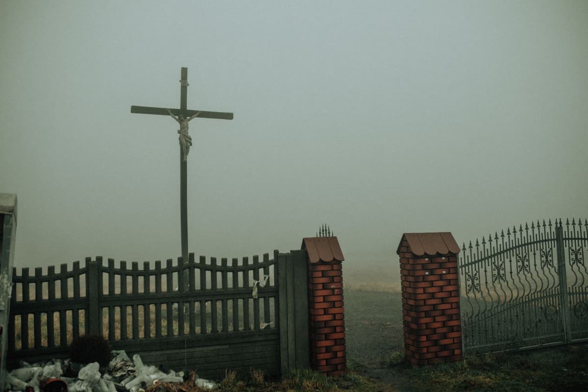 a heavy iron gate closing on a foggy forest road