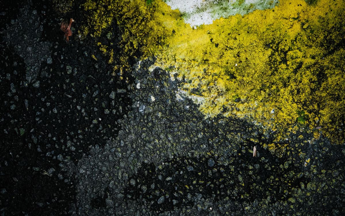 bright neon yellow stripes on a stark black asphalt road