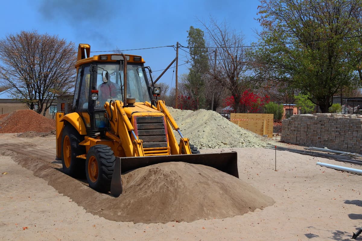 a yellow excavator parked next to a stone canal trench
