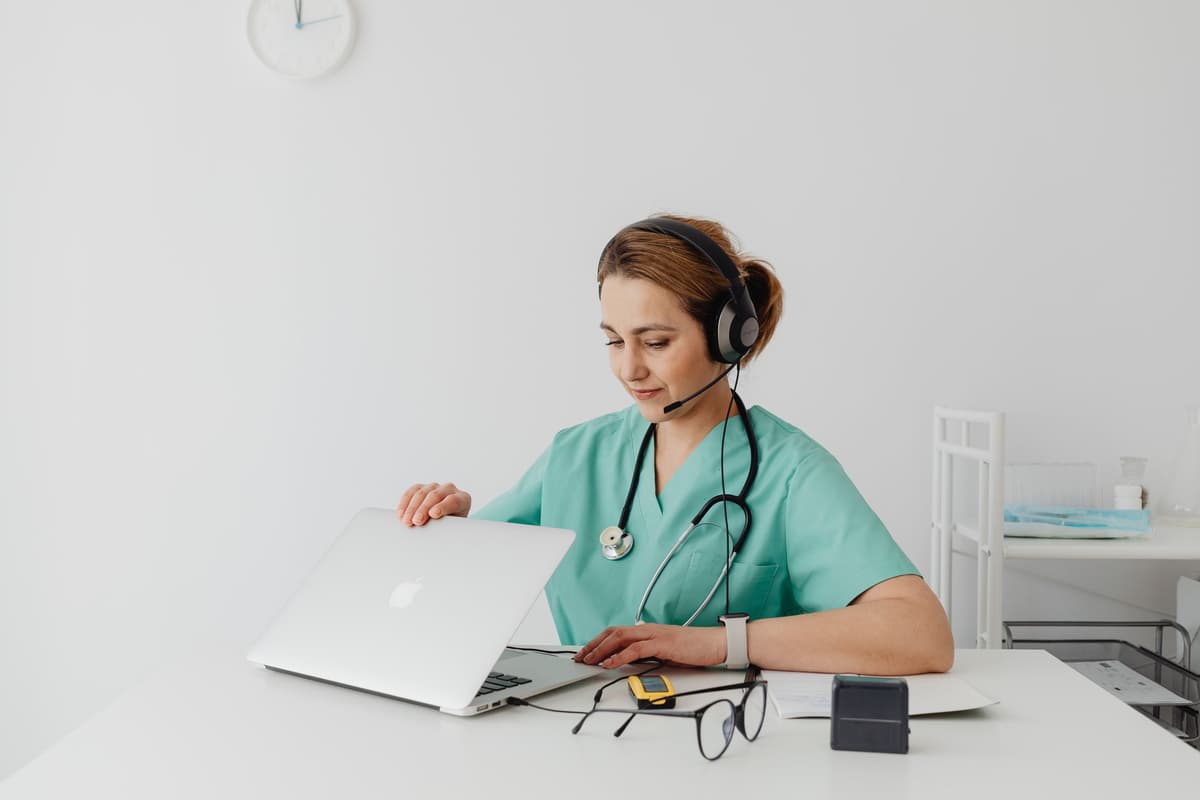 a person typing on a laptop while wearing a stethoscope
