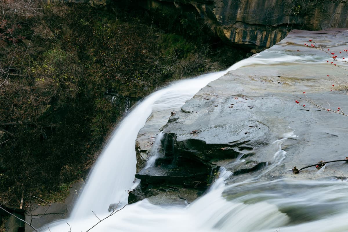 close-up of water rushing over dark stone ledge