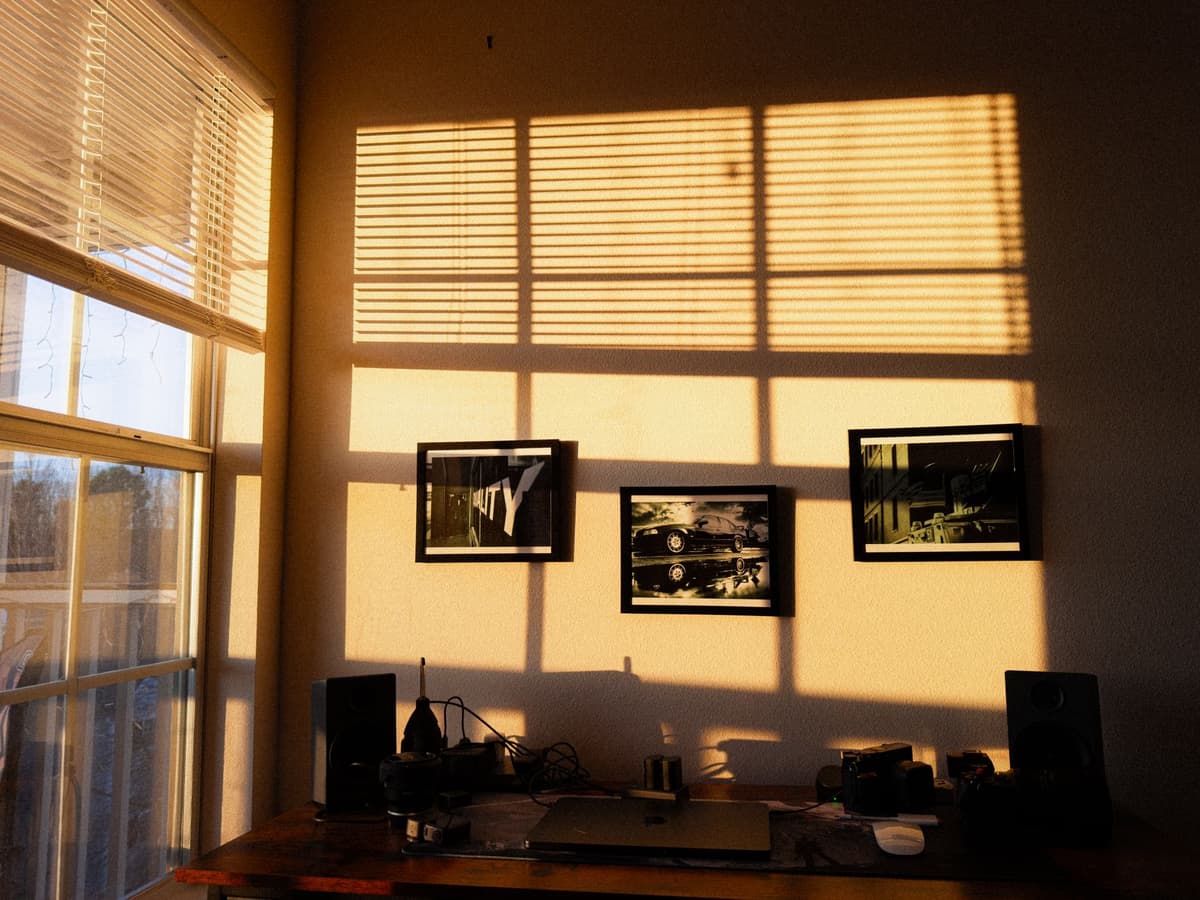 a single lit candle on a desk cluttered with computer monitors