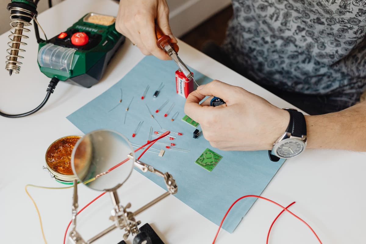 person soldering a small green circuit board