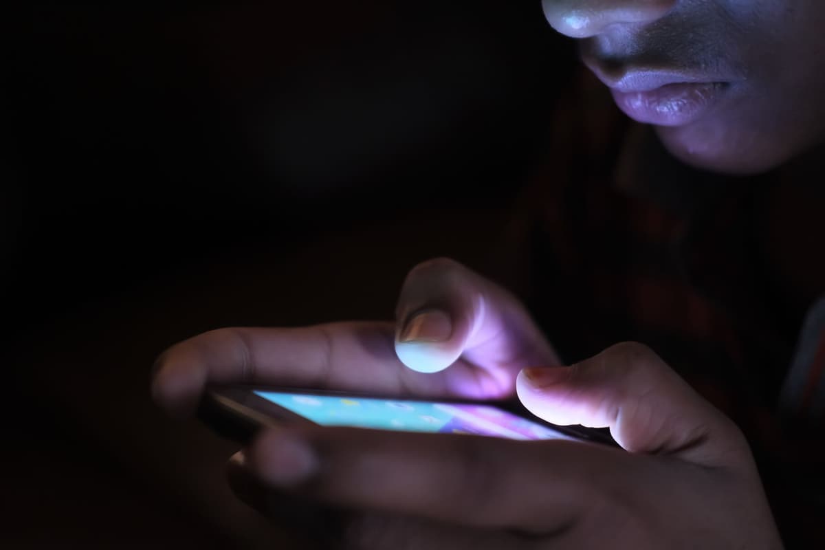 a hand holding a glowing smartphone in a dark room